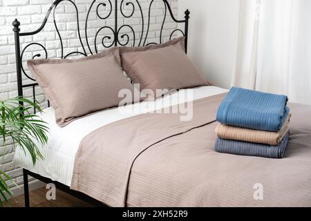 Stacked Blue and Beige Blankets on a Made Bed Stock Photo