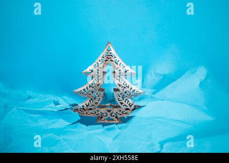Silver metallic fir tree structure emerging thru ripped paper hole, blue crumpled background, Stock Photo
