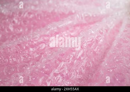 Plastic bubble wrap foil creases and waves on pink background, abstract textured backdrop, soft focus Stock Photo