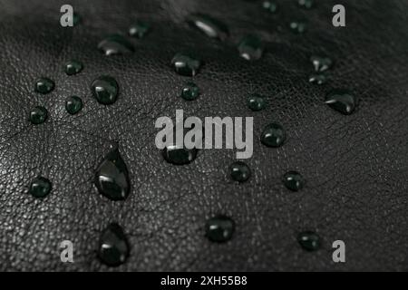 Round water drops on black leather texture, side view, soft focus Stock Photo