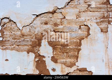 Texture of a deteriorating wall, where worn-out paint exposes the historic brick underneath. Stock Photo