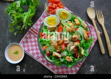 A cesar salad bowl filled with lettuce, tomatoes, egg and chicken. The salad is served in a clear glass bowl Stock Photo