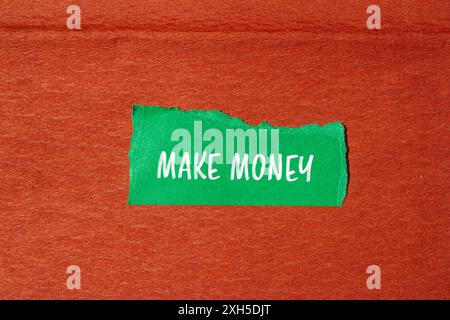 Make money message written on ripped torn green paper piece with brown background. Conceptual make money symbol. Copy space. Stock Photo