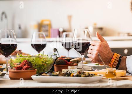Man giving thumbs up approving delicious food and wine during dinner party Stock Photo