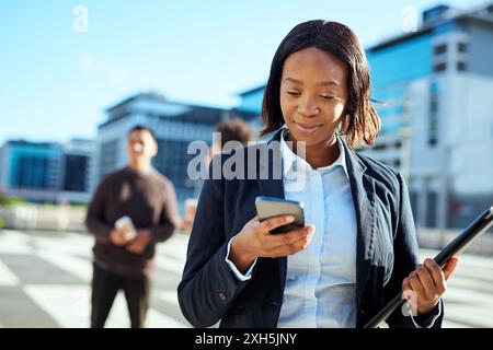 Diverse Group of Business Professionals in Urban Area, Female Entrepreneur Using Smartphone Stock Photo