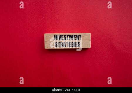 Investment strategies message written on wooden block with redbackground. Conceptual investment strategies symbol. Copy space. Stock Photo