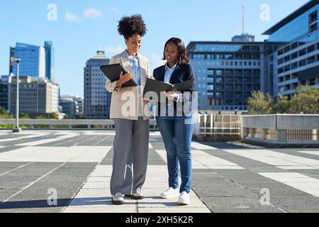 Diverse Businesswomen Walking in the City with Laptops Discussing Work Stock Photo