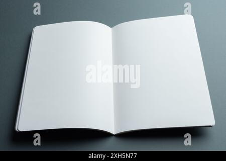 An open blank notebook lies on a gray background with copy space. Ideal for designers to mock up text and graphics due to the clean, open pages. Stock Photo