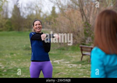 Sport woman stretching arms outdoors with her personal trainer before exercising Stock Photo