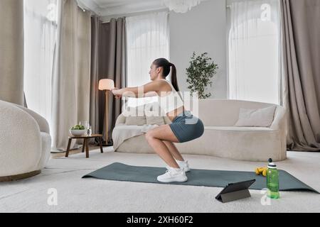 Young woman in doing active workout, squats exercises Stock Photo