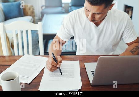 Remote work, laptop and man with documents at table for review, sentence structure or editing. Proofreading, freelance and person for check grammar Stock Photo