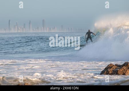 Surfer riding wave with Gold Coast skyline in the background Stock Photo