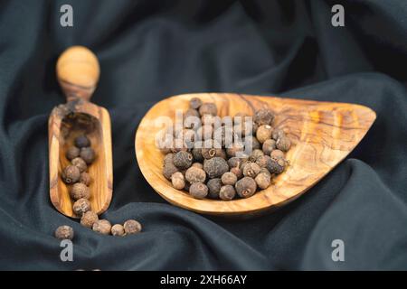 allspice, pimento (Pimenta dioica), dried fruit on a wooden bowl and wooden scoop Stock Photo