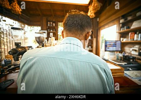 barista preparing coffee in the coffee machine. View from the back. Stock Photo