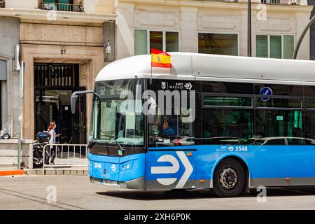 06.19.2024, Madrid, Spain: Madrid blue public bus in the street with Spanish flag attached on the side and waving Stock Photo