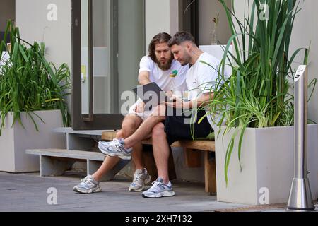 Two men sitting together with laptop in street cafe. Life in summer city, team work Stock Photo