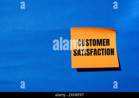 Customer satisfaction message written on orange paper with blue background. Conceptual customer satisfaction symbol. Copy space. Stock Photo