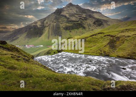 Skogafoss fall river flowing through a green valley with a mountain . Iceland Stock Photo