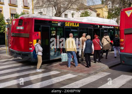 Seville, Spain. February 5, 2024 - Passengers boarding a red city bus at a bus station Stock Photo