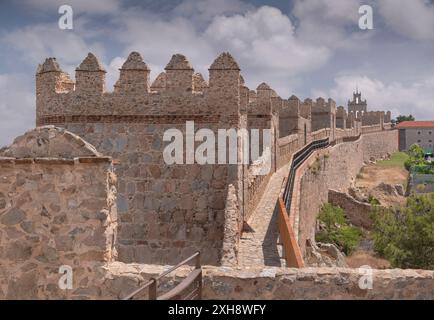 Spain, Castile and Leon, Avila, City walls that were built from 1090 onwards and are among the best-preserved and most complete in Europe, viewed from the walkway along the interior perimeter of the walls with the brick steeple of the former Carmelite convent El Carmen in the far distance. Stock Photo