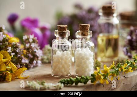 Homeopathic pills or globules in two glass bottles with various summer flowers on a table Stock Photo