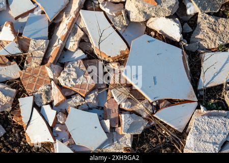 Ceramic light blue and white tiles broken into small sharp pieces, thrown on the volcanic soil in the nature. Lanzarote, Canary Islands, Spain. Stock Photo