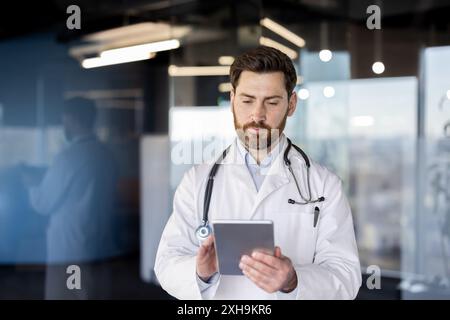 Focused doctor using a digital tablet in modern hospital office. Medical professional reviewing patient information, conducting research, or managing healthcare tasks. Technology healthcare setting. Stock Photo