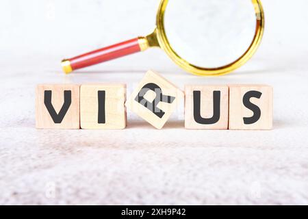 VIRUS word alphabet letters assembled from wooden cubes with a magnifying glass in the background without focus Stock Photo