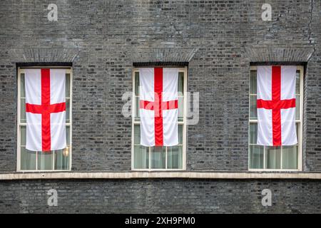 London, 12th July 2024. Three large St George's flags, the flag of England, were added to windows just above the No 10 Downing Street door, likely to symbolise the three lions (the common name for the England football team. The flags were added to the two rows of St George's cross bunting which were put up around the door and railings for the quarter final game. England play Spain in the final on Sunday. Credit: Imageplotter/Alamy Live News Stock Photo