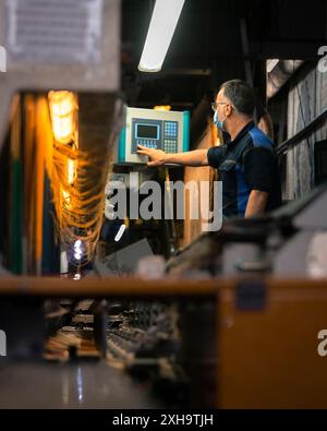 Industrial worker operating machinery in a modern factory setting. Stock Photo