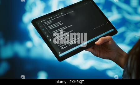 Software developer with tablet programming artificial intelligence computing simulating human brain. Close up of IT professional using device, building AI machine learning algorithms, camera A Stock Photo