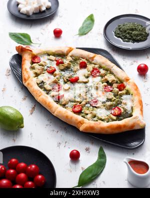 Freshly baked pesto and tomato Turkish pide on a white background Stock Photo