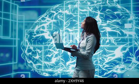 Software developer solving tasks on laptop, running artificial intelligence programming scripts. Woman using notebook to write lines of code for AI applications development, camera B Stock Photo