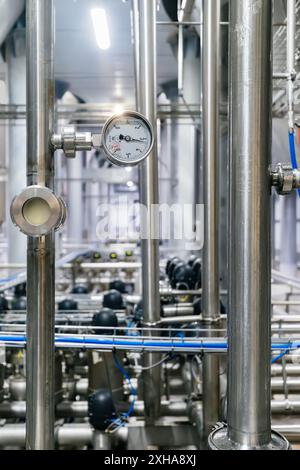 Large industrial stainless steel pipes and pressure gauge in modern brewery. Stock Photo