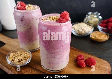 Banana Raspberry Smoothies in Tumbler Glasses: Ombre pink smoothies with raspberries and granola garnish Stock Photo