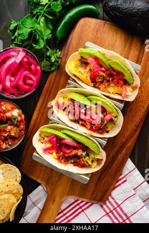 Tex-Mex Migas Breakfast Tacos in a Taco Holder: Overhead view of breakfast tacos with eggs, sliced avocado, pickled onions, and salsa Stock Photo