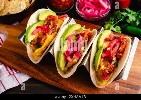 Tex-Mex Migas Breakfast Tacos in a Taco Holder: Overhead view of breakfast tacos with eggs, sliced avocado, pickled onions, and salsa Stock Photo