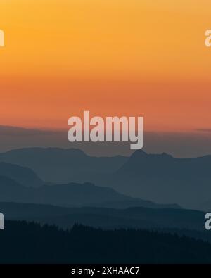 A dramatic sunset with the langdale pikes creating layers as the are silhouetted in the Lake District haze Stock Photo