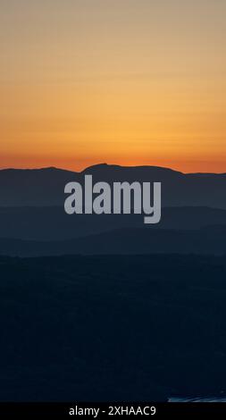 A sunset landscape photo taken from gummers how at viewpoint which shows the Lake District fells at a dramatic golden hour. Stock Photo