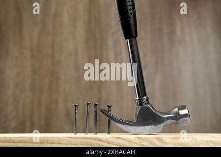 Hammer pulling metal nail out of plank against wooden background, space for text Stock Photo