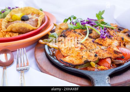 A view of chicken fajitas served in a skillet, with a side of rice and beans. Stock Photo