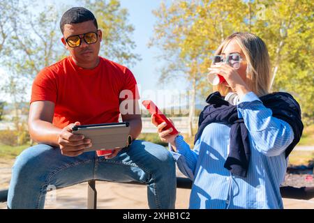 A young smiling multiracial couple holding smart phone and digital tablet, Stock Photo