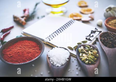 Herbs, spices and seasoning on table with notebook, inspiration and flavor for cooking technique for culinary. Cookbook, instructions and food recipe Stock Photo