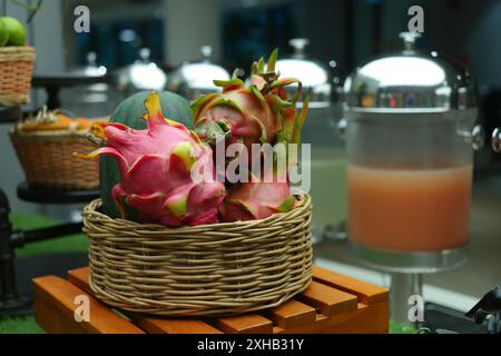 Dragon fruit and melon in a wicker basket on a wooden table Stock Photo