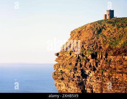 O’Briens Tower on top of the sheer Cliffs of Moher, County Clare, west Ireland. Sailboat yacht in distance. Atlantic Ocean Stock Photo