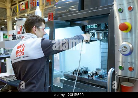 Man worker working with a CNC milling machine, stand. Industry Exhibition. Kyiv, Ukraine Stock Photo