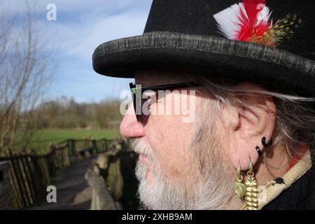 Profile of a fashion-conscious man of 71 with beard, glasses, top hat and earrings Stock Photo
