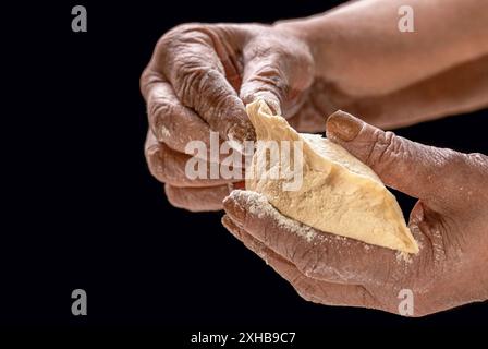 Process of making pies, hand. Old woman hands rolling doughs for pies. Hands pie dough. Cooks dough for baking, pieces of raw dough. Stock Photo