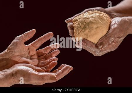 Hands with slice of whole wheat bread. Helping the homeless. Woman giving poor homeless person pieces of bread, donations, closeup. Stock Photo