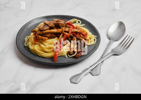 Plate with spaghetti with mushrooms and pork in sticky sauce Stock Photo